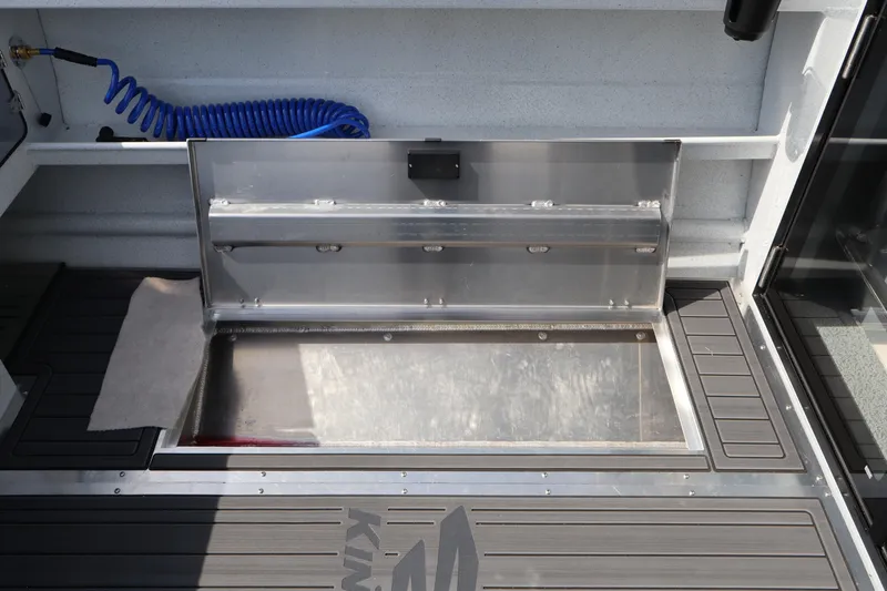 Slide: The Image of Open storage compartment on 2026 KingFisher 25 XAC boat deck with blue coiled hose. - 12