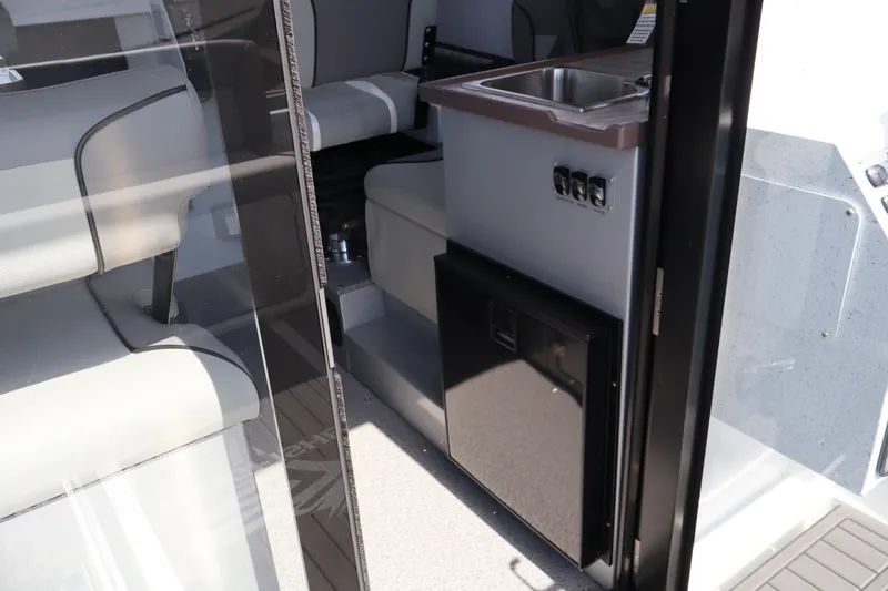 Slide: The Image of Interior view of 2026 KingFisher 25 XAC boat, featuring seating and compact kitchenette. - 18