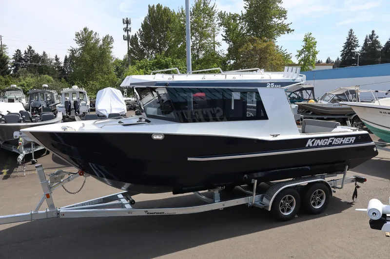 Slide: The Image of 2026 KingFisher 25 XAC boat on trailer, parked outdoors with trees in background. - 3