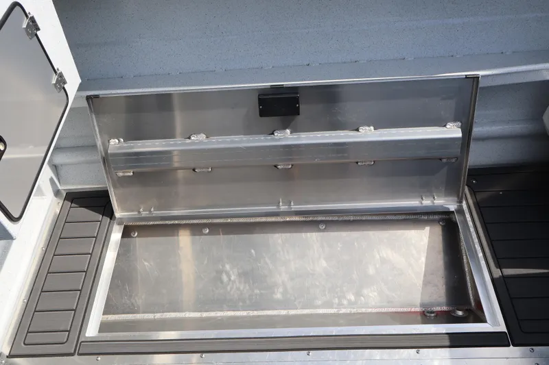 Slide: The Image of Open storage compartment on 2026 KingFisher 25 XAC boat, showcasing sleek metal design. - 9