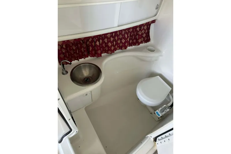 Slide: The Image of 2002 Formula 280 Bowrider boat bathroom with sink and toilet, featuring red curtain. - 32