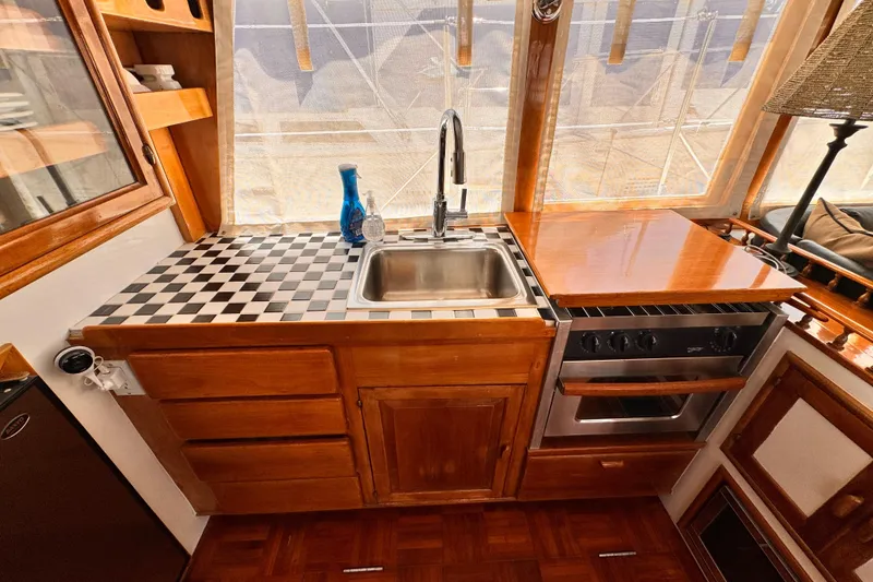 Slide: The Image of 1978 Roughwater 41 yacht kitchen with wood cabinetry, sink, stove, and checkered countertop. - 15