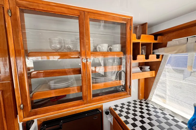 Slide: The Image of 1978 Roughwater 41 yacht interior with wooden cabinets, glassware, and checkered countertop. - 16