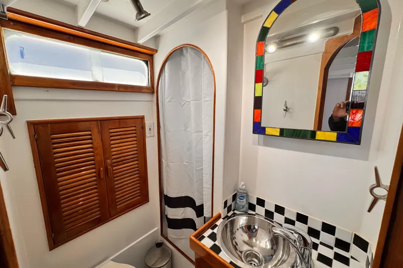 Slide: The Image of 1978 Roughwater 41 boat bathroom with colorful mirror, stainless sink, and wooden accents. - 24