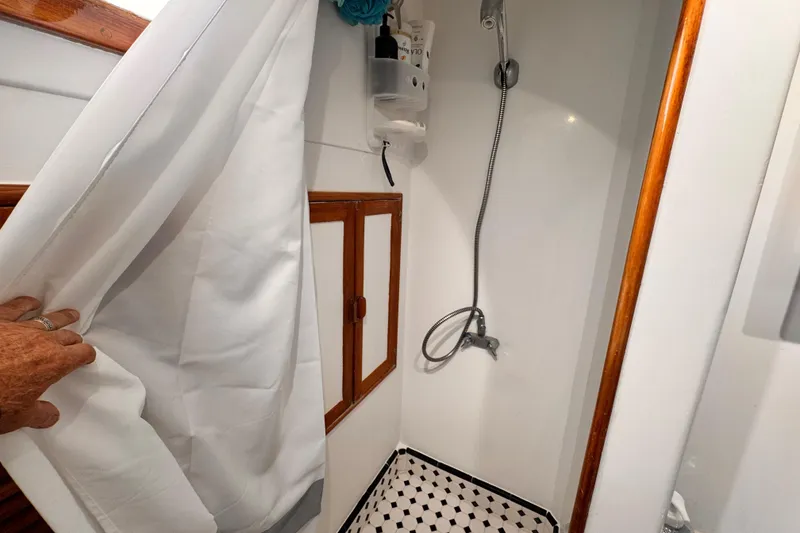 Slide: The Image of 1978 Roughwater 41 boat shower with white curtain and wooden accents. - 26