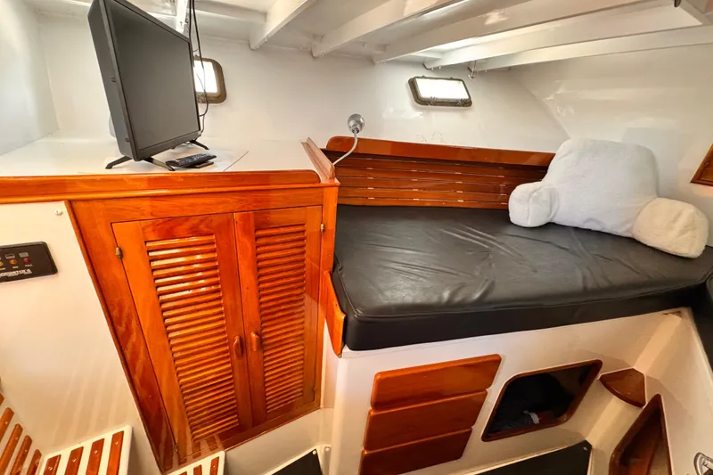 Slide: The Image of 1978 Roughwater 41 boat interior with wooden cabinetry, cushioned seating, and mounted TV. - 31