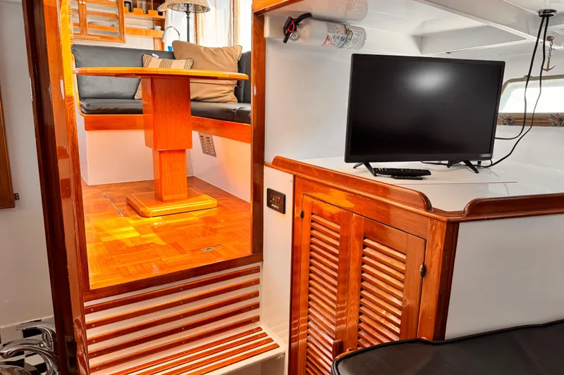 Slide: The Image of 1978 Roughwater 41 yacht interior with wooden dining area and TV setup. - 32