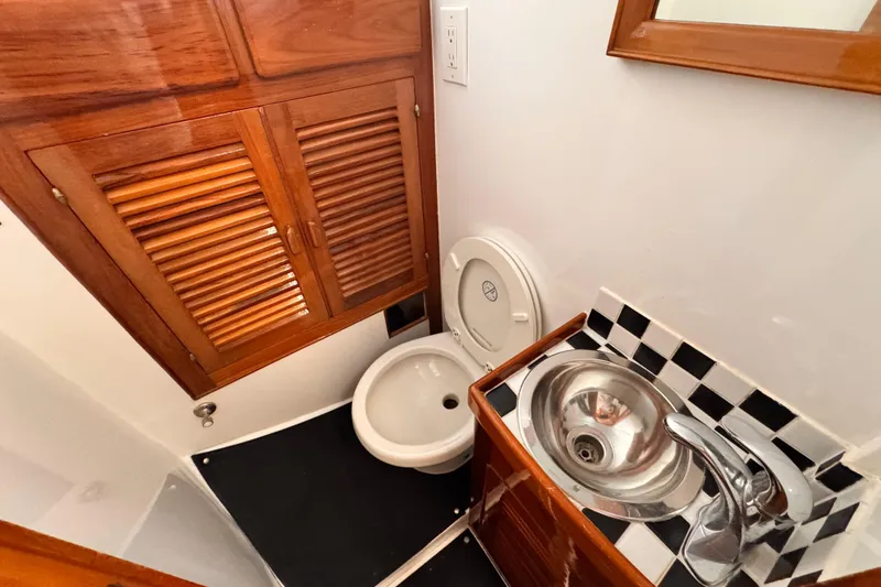 Slide: The Image of 1978 Roughwater 41 boat bathroom with wooden cabinets, toilet, and stainless steel sink. - 35