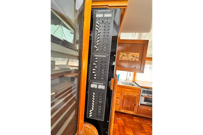 Slide: The Image of Electrical panel inside a 1978 Roughwater 41 boat, featuring wooden cabinetry and kitchen area. - 51