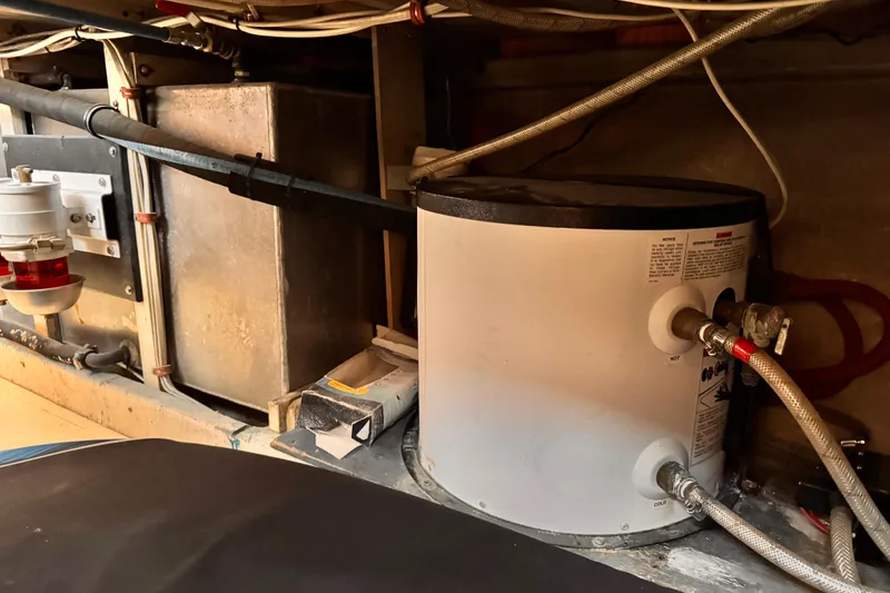 Slide: The Image of Engine room of a 1978 Roughwater 41 boat, featuring a water heater and fuel filter system. - 60