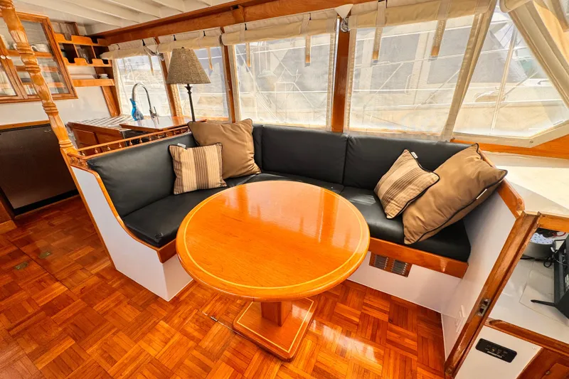 Slide: The Image of Cozy seating area in a 1978 Roughwater 41 boat with wooden table and cushions. - 7