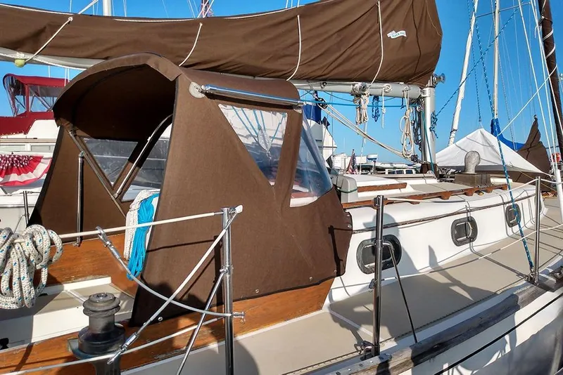 The Image of 1984 Cape Dory 31C sailboat with brown canvas cover docked at marina. - 1