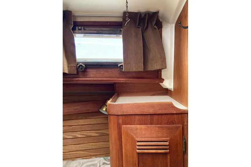 Slide: The Image of Interior of 1984 Cape Dory 31C sailboat with wooden cabinetry and window curtains. - 16