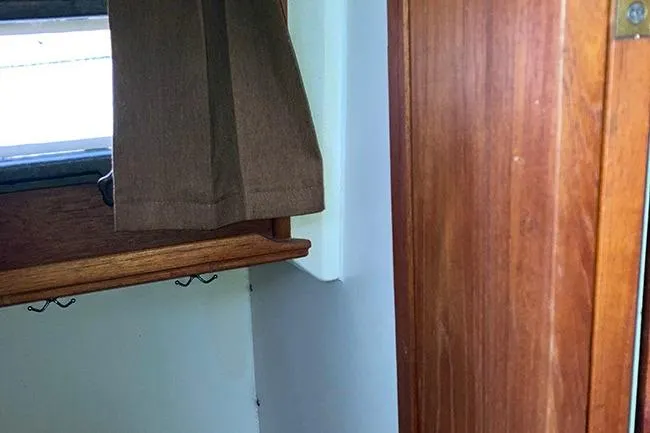Slide: The Image of Interior view of a 1984 Cape Dory 31C sailboat with wooden paneling and curtain. - 18