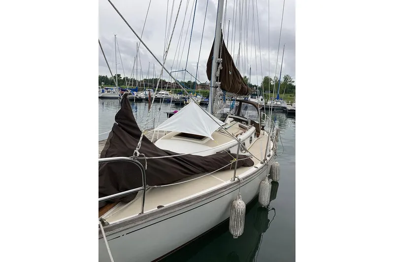 Slide: The Image of 1984 Cape Dory 31C sailboat docked in a marina, featuring brown sails and fenders. - 3