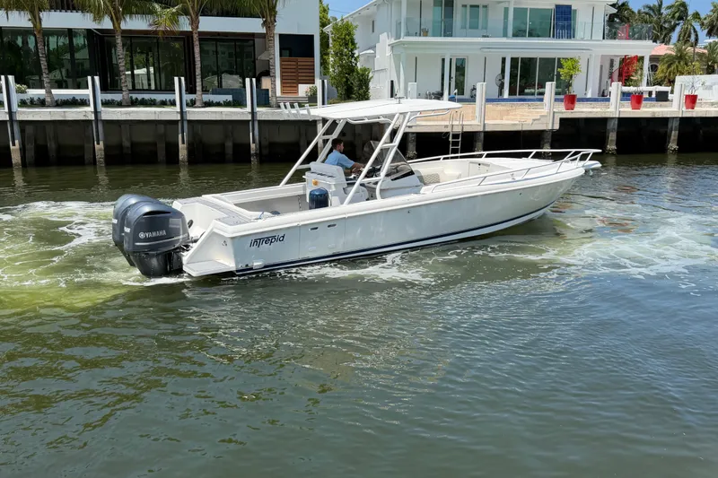 Slide: The Image of 2003 Intrepid 323 Cuddy boat cruising near waterfront homes. - 10