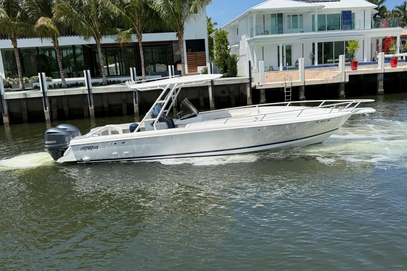 Slide: The Image of 2003 Intrepid 323 Cuddy boat cruising near waterfront homes. - 11