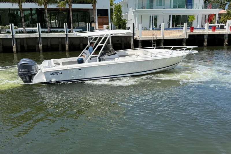 Slide: The Image of 2003 Intrepid 323 Cuddy boat cruising near waterfront homes. - 12