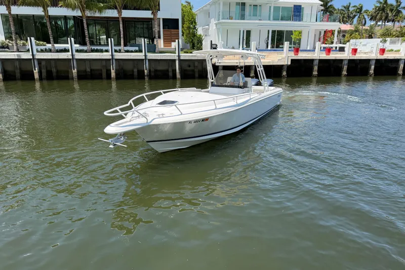 Slide: The Image of 2003 Intrepid 323 Cuddy boat cruising near waterfront homes. - 14