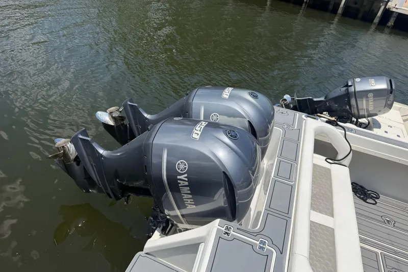 Slide: The Image of Twin Yamaha outboard engines on a 2003 Intrepid 323 Cuddy boat docked by water. - 15