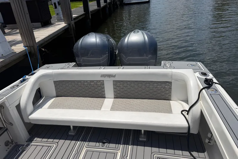 Slide: The Image of 2003 Intrepid 323 Cuddy boat with dual engines and cushioned seating at dock. - 19