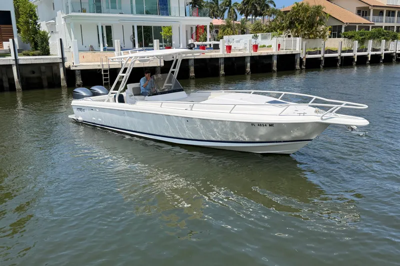Slide: The Image of 2003 Intrepid 323 Cuddy boat cruising near waterfront homes. - 2