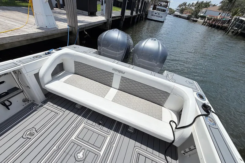 Slide: The Image of 2003 Intrepid 323 Cuddy boat with cushioned seating and twin engines docked by the water. - 20