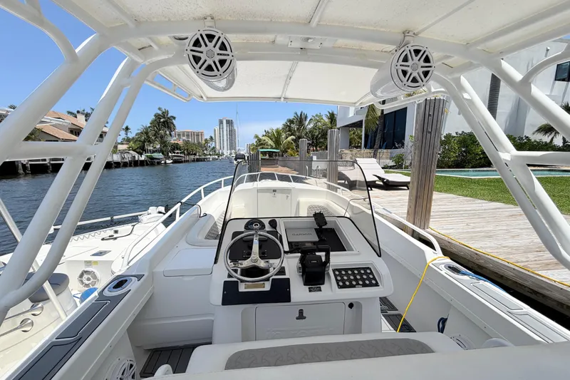 Slide: The Image of 2003 Intrepid 323 Cuddy boat cockpit with steering wheel, docked by a canal. - 27