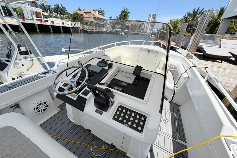 Slide: The Image of 2003 Intrepid 323 Cuddy boat cockpit with Garmin navigation, docked by waterfront homes. - 28
