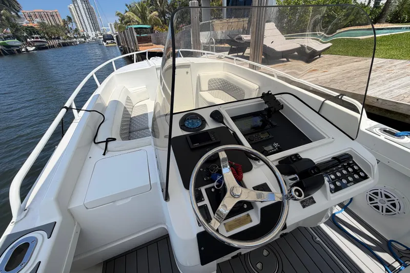Slide: The Image of 2003 Intrepid 323 Cuddy boat cockpit with steering wheel and control panel, docked by a canal. - 29