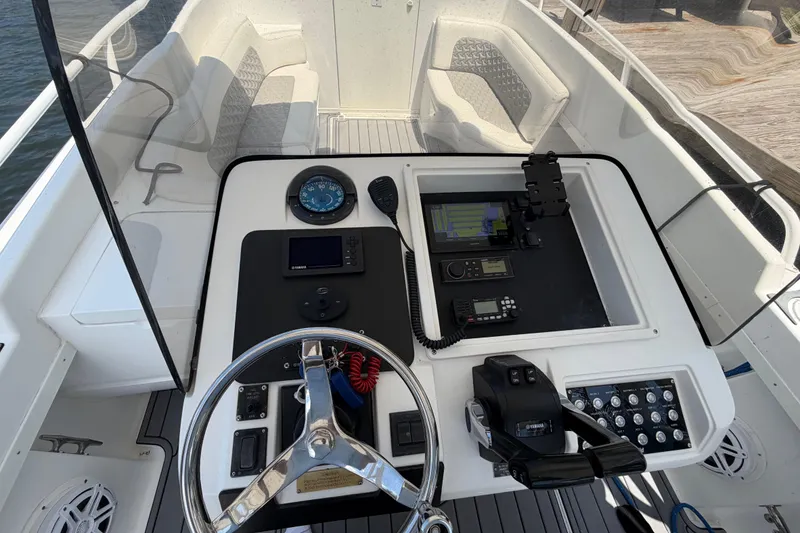 Slide: The Image of 2003 Intrepid 323 Cuddy boat cockpit with steering wheel, navigation instruments, and seating area. - 31