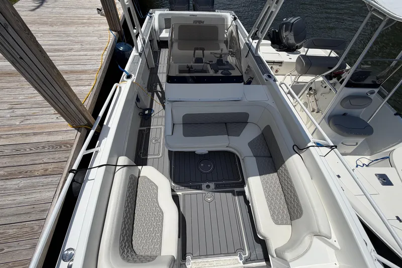 Slide: The Image of 2003 Intrepid 323 Cuddy boat interior with cushioned seating and deck, docked by wooden pier. - 35