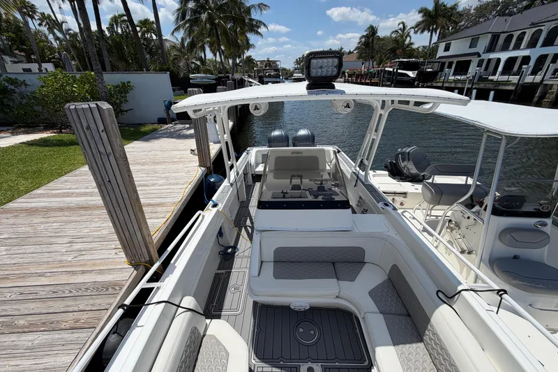 Slide: The Image of 2003 Intrepid 323 Cuddy boat docked by a wooden pier, surrounded by palm trees. - 36