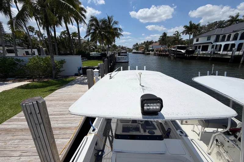 Slide: The Image of 2003 Intrepid 323 Cuddy docked by a scenic waterfront with palm trees. - 37
