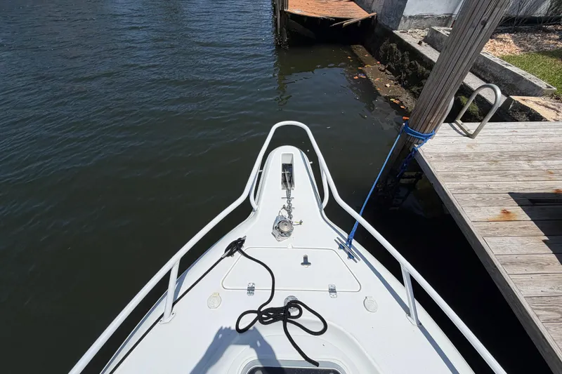Slide: The Image of Bow view of a 2003 Intrepid 323 Cuddy boat docked by wooden pier. - 39