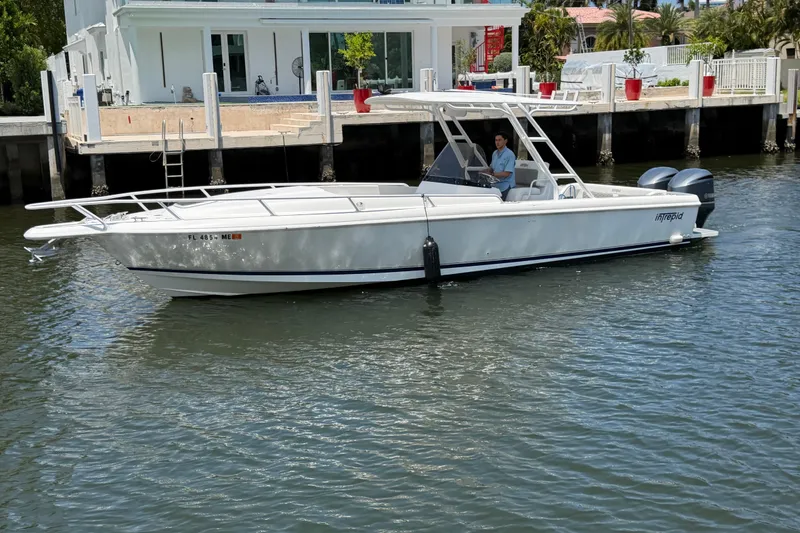 Slide: The Image of 2003 Intrepid 323 Cuddy boat on water near a waterfront property. - 6