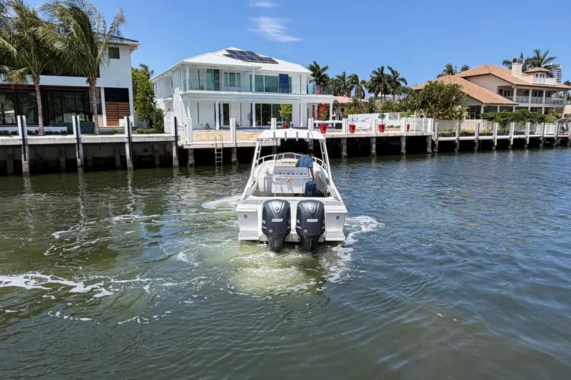 Slide: The Image of 2003 Intrepid 323 Cuddy cruising near waterfront homes under a clear blue sky. - 7