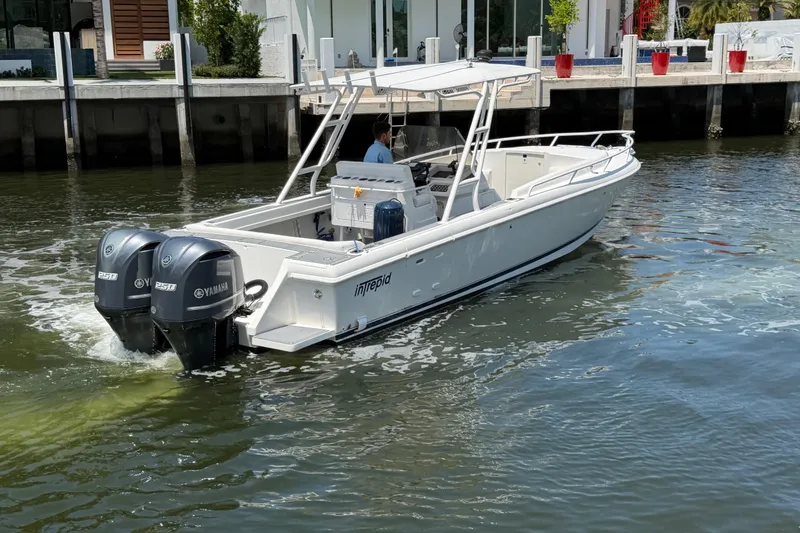 Slide: The Image of 2003 Intrepid 323 Cuddy boat with dual Yamaha engines on water near dock. - 8