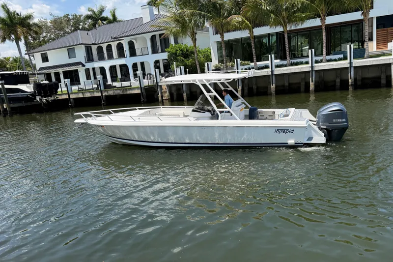 Slide: The Image of 2003 Intrepid 323 Cuddy boat cruising near waterfront homes with palm trees. - 9