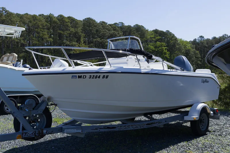 Slide: The Image of 2006 Edgewater 170CC boat on trailer, parked outdoors with trees in background. - 5