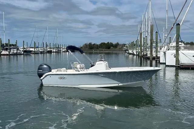 Slide: The Image of 2022 Sea Hunt Ultra 219 boat docked in a marina with sailboats in the background. - 3
