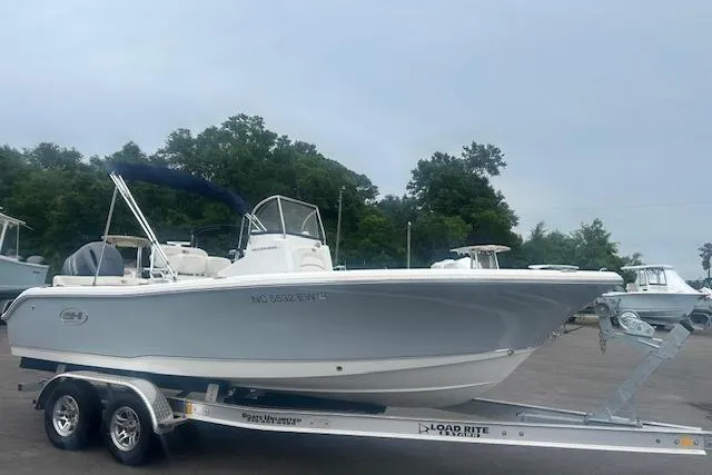 Slide: The Image of 2022 Sea Hunt Ultra 219 boat on trailer, parked outdoors with trees in background. - 4
