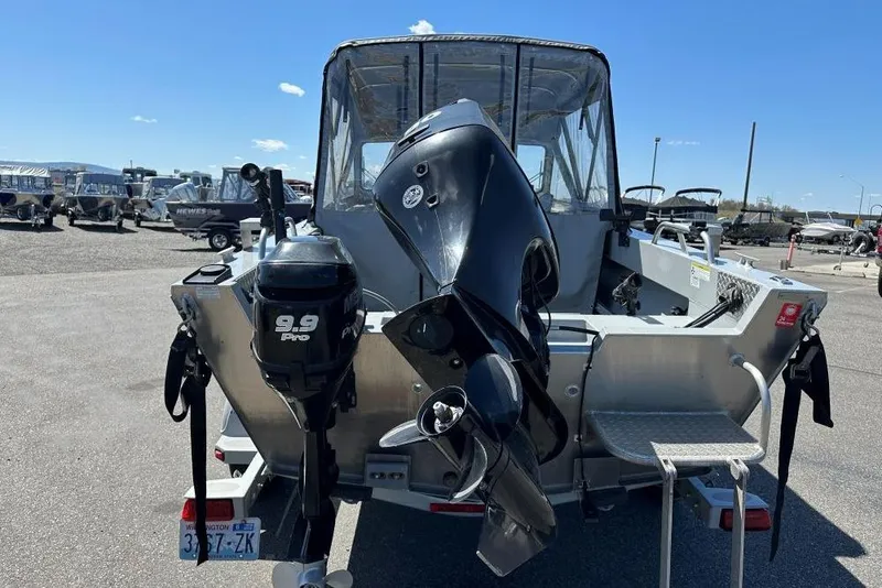 Slide: The Image of 2015 Hewescraft 180 Sportsman boat with dual outboard motors in a parking lot. - 3