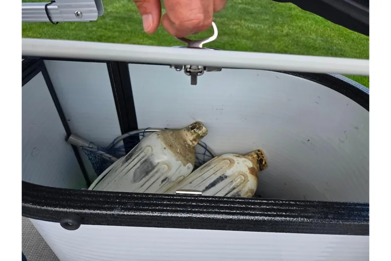 Slide: The Image of Open storage compartment on 2023 Crest Classic LX 200 boat with vintage jugs inside. - 15
