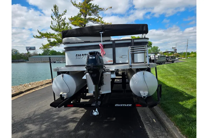 Slide: The Image of 2023 Crest Classic LX 200 pontoon boat on trailer by a lakeside. - 2