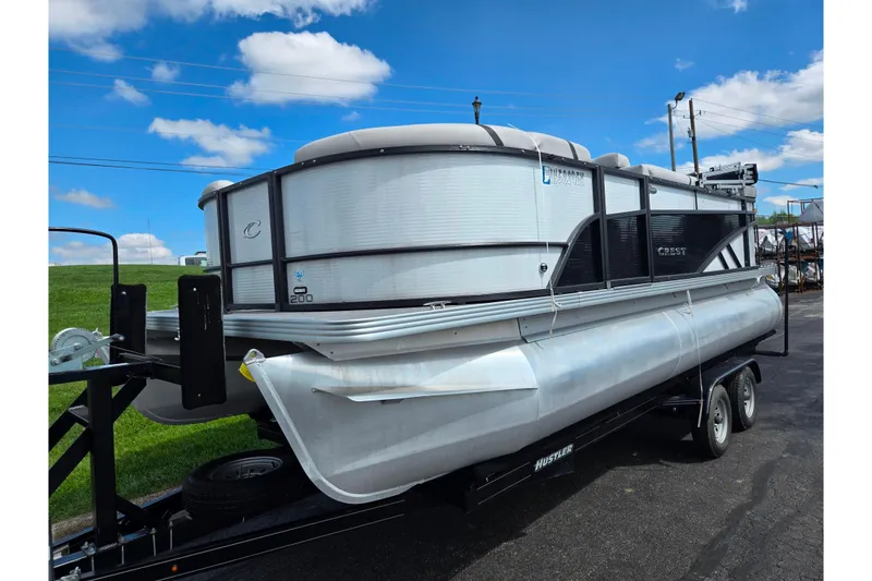 Slide: The Image of 2023 Crest Classic LX 200 pontoon boat on trailer under blue sky. - 5