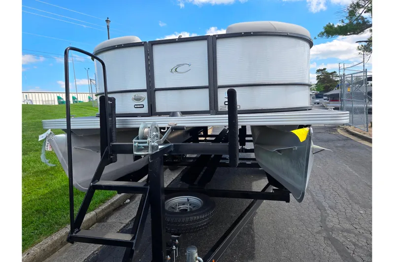Slide: The Image of 2023 Crest Classic LX 200 pontoon boat on trailer, parked outdoors. - 6