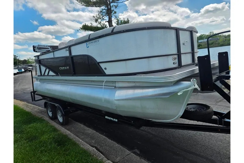 Slide: The Image of 2023 Crest Classic LX 200 pontoon boat on trailer by a lake. - 8