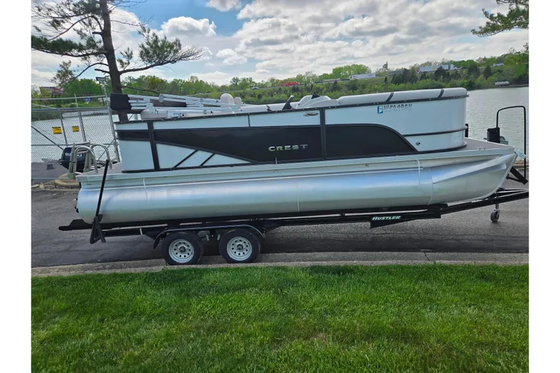 Slide: The Image of 2023 Crest Classic LX 200 pontoon boat on trailer by a lakeside. - 9