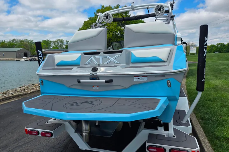 Slide: The Image of 2023 ATX Surf Boats 20 Type-S, blue and gray, docked by a lake. - 2
